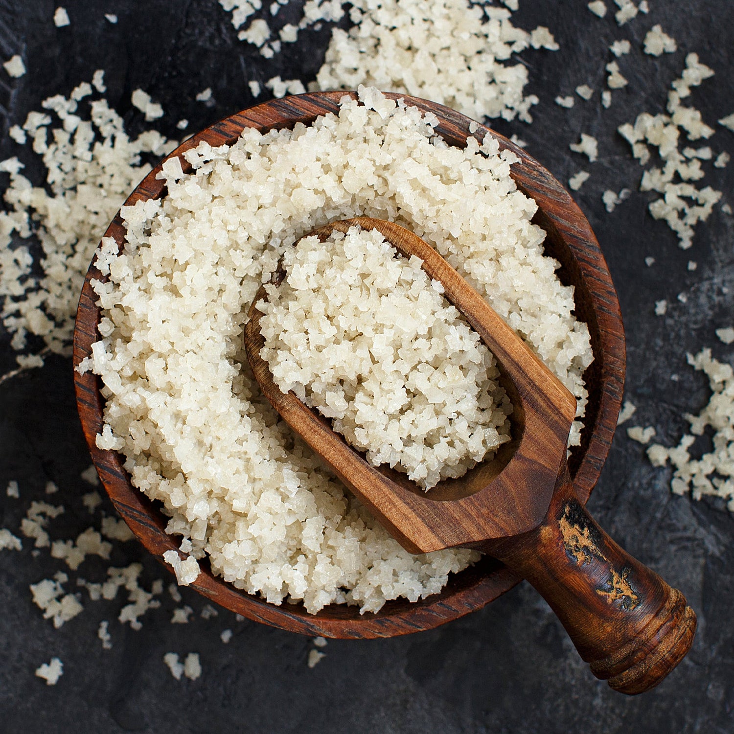 A wooden spoon filled with Celtic Salt sits on top of a wooden bowl filled to the brim with Nano Celtic Sea Salt.